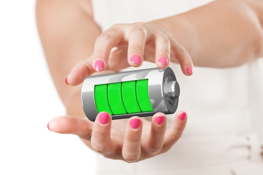 Hands holding a fully charged green battery in mid-air